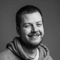 Black and white photo of a caucasian man around 30 years old in hoodie, smiling