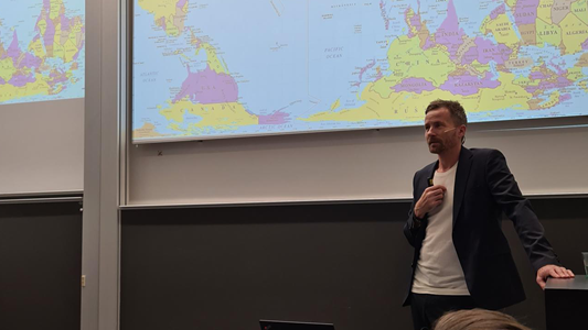 Mikkel Flyverbom standing in front of a world map